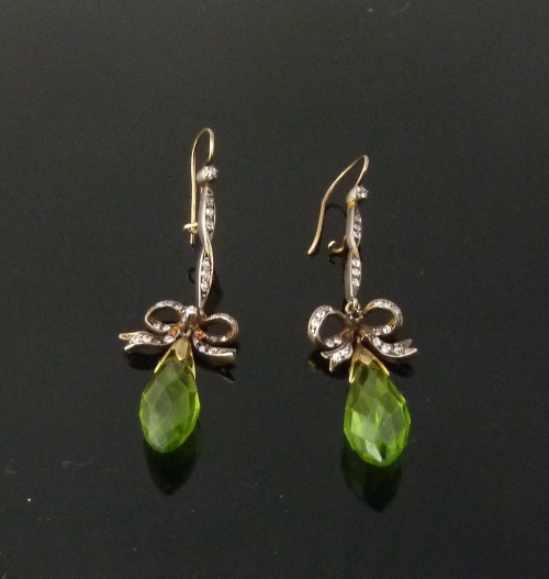 A pair of peridot and diamond ear pendants, the diamond set bails above a diamond set ribbon tie and