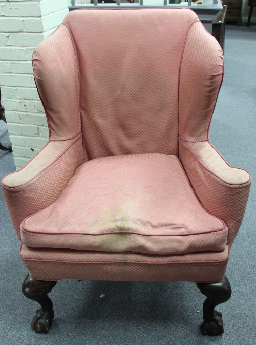 A wing back armchair of George II design on ball and claw feet