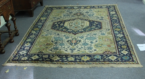 A Caucasian carpet, the central indigo medallion on an ivory ground within a border of stylised