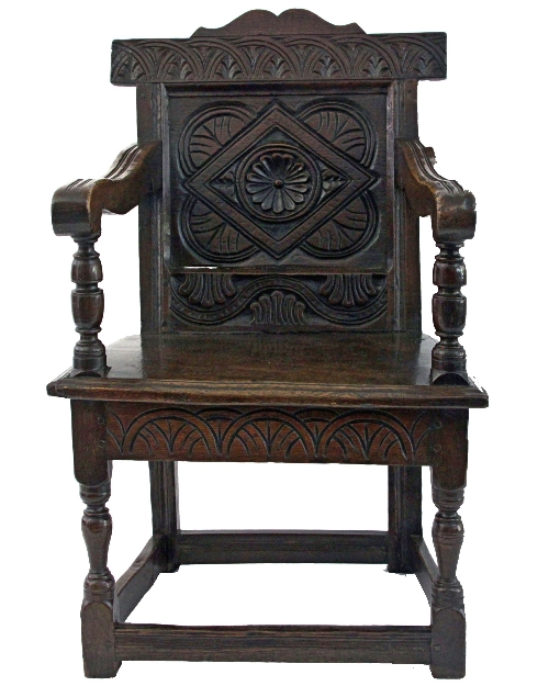 A small 17th Century oak wainscot armchair, possibly West Country, with carved cresting to carved
