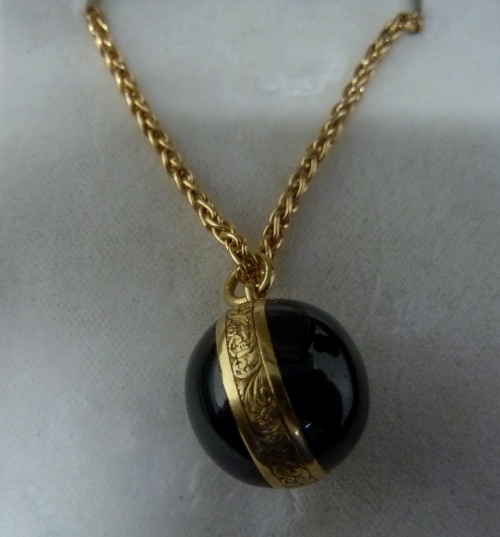 A Victorian garnet locket of globe form, enclosing a locket of hair to one side and engraved to