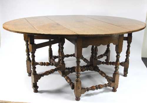 A large oak double gateleg table of 17th Century design, the oval two-flap top on baluster turned