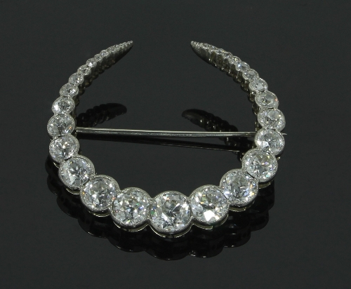 An Edwardian diamond crescent brooch, the graduated stones in a millegrain setting, in a fitted