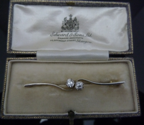 A diamond crossover bar brooch, in an 18ct white gold fronted setting, in a case from Edward & Sons,