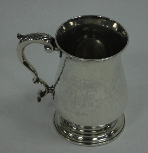 A George III silver mug, London 1776, of baluster form with leaf capped scroll handle, approximately