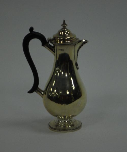 A silver hot water jug, TB, London 1897, of pear shape with beaded borders and with ebonised handle,