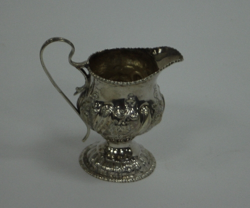 A George III silver jug, maker's mark rubbed, London 1763, with later embossed decoration on a domed