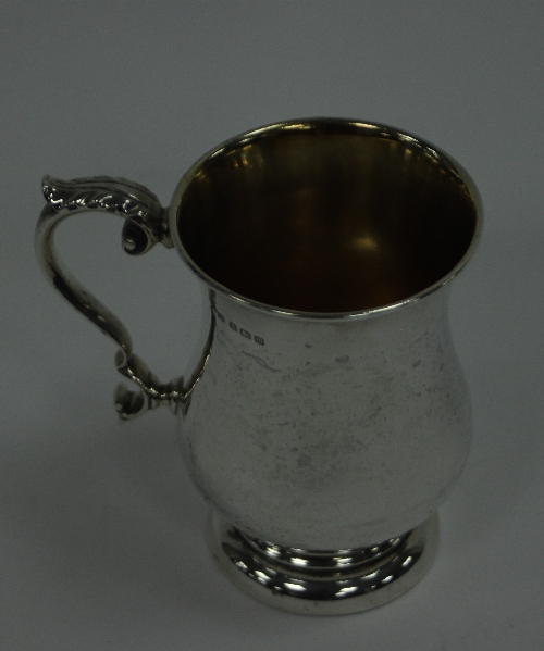 A silver mug, Birmingham 1911, of baluster form with leaf capped scroll handle, approximately 220gm