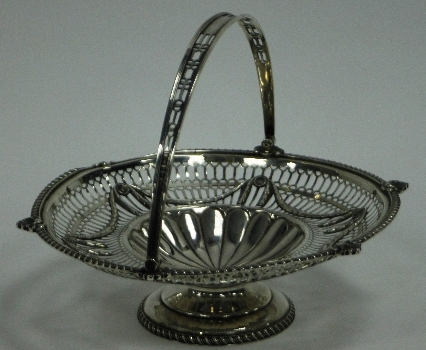An Edwardian silver cake basket, Goldsmiths and Silversmiths Co., London 1908, with swing handle and