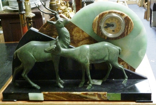 A large Art Deco clock, the polished slate, onyx and hardstone stand mounted with two spelter