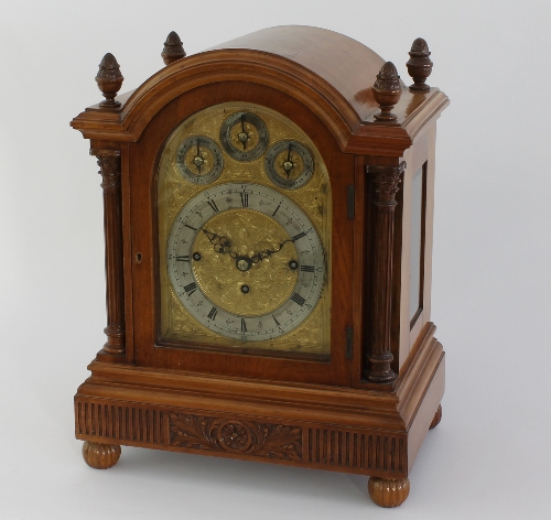 An Edwardian walnut eight-day mantel clock, the arch top case with pineapple finials and