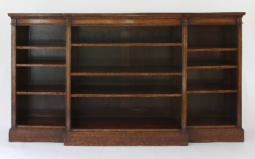 A Gillow and Co. burr oak breakfront library bookcase fitted adjustable shelves, the top with