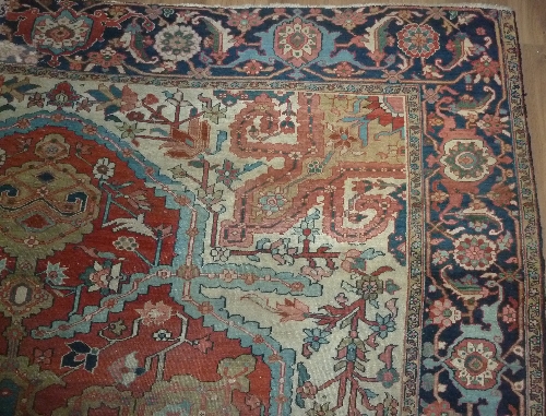 A Heriz carpet with central geometric medallion on a red ground within a floral camel ground