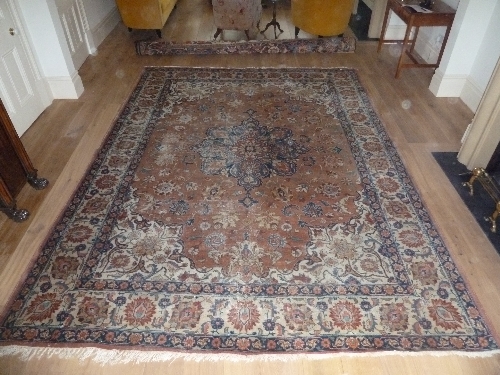 A Tabriz carpet with blue ground central medallions and floral puce ground within a palmette border,