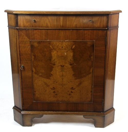 A walnut corner cupboard, fitted a secretaire drawer above a cupboard, bearing a Maple label, on