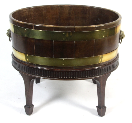 A George III style mahogany wine cooler, circa 1760, the oval brass bound cooler with lion mask ring