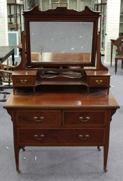 An Edwardian mahogany and satinwood banded dressing chest, the mirror back with two short drawers,
