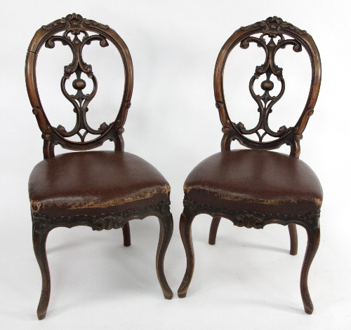 A set of five Victorian walnut dining chairs, with pierced carved oval backs, upholstered seats