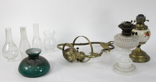 A hanging brass lantern with green opaque shade, two oil lamps and four chimneys