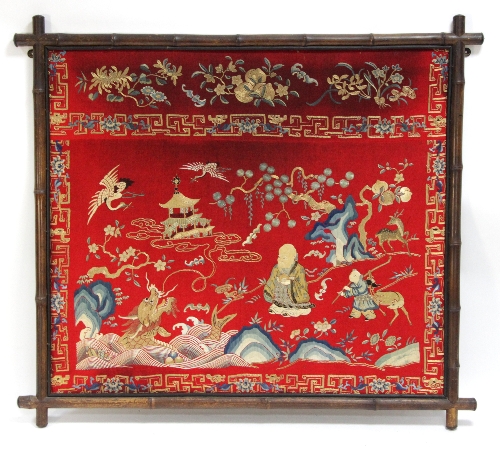 A Chinese needlework picture sewn in silk with deity in landscape and dragon in bamboo frame, 86cm x