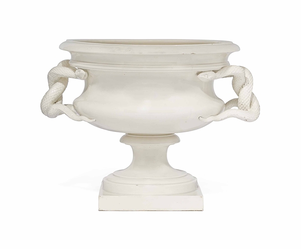 AN ENGLISH CREAM GLAZED CERAMIC JARDINIERE 
20TH CENTURY 
With entwined serpent handles 
15 in. (