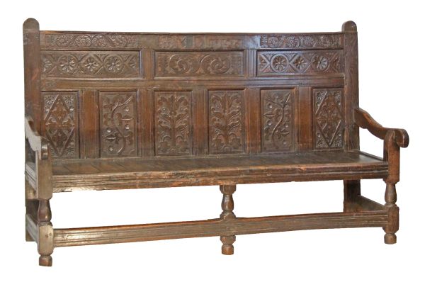 Early 18th Century oak North Country settle of joined construction, the panel back with carved