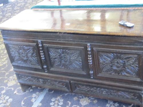 An 18th century style oak coffer with carved three panel front and two drawers under.