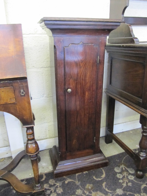 A narrow oak cupboard with single door.