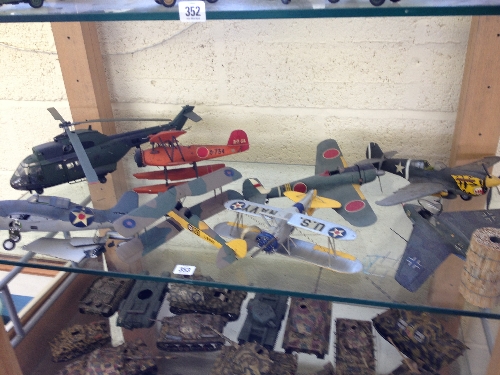 A shelf containing eight various hand painted and kit built models of WWII and other MIlitary