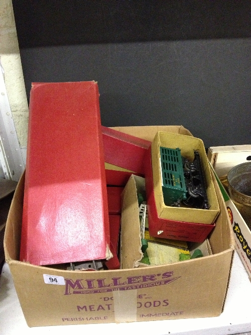 A box containing various Hornby tinplate 0 gauge railway items and track.