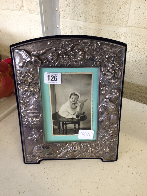 A modern silver photograph frame with embossed bird and foliage decoration.