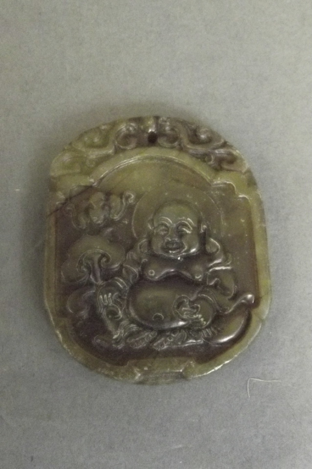 A Chinese jade pendant carved in the form of a seated Buddha, 2'' long