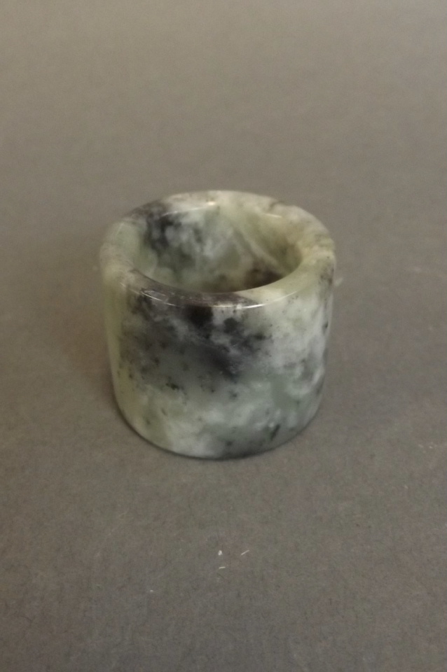 A Chinese mottled spinach and jade archers ring, 1'' x 1¼''