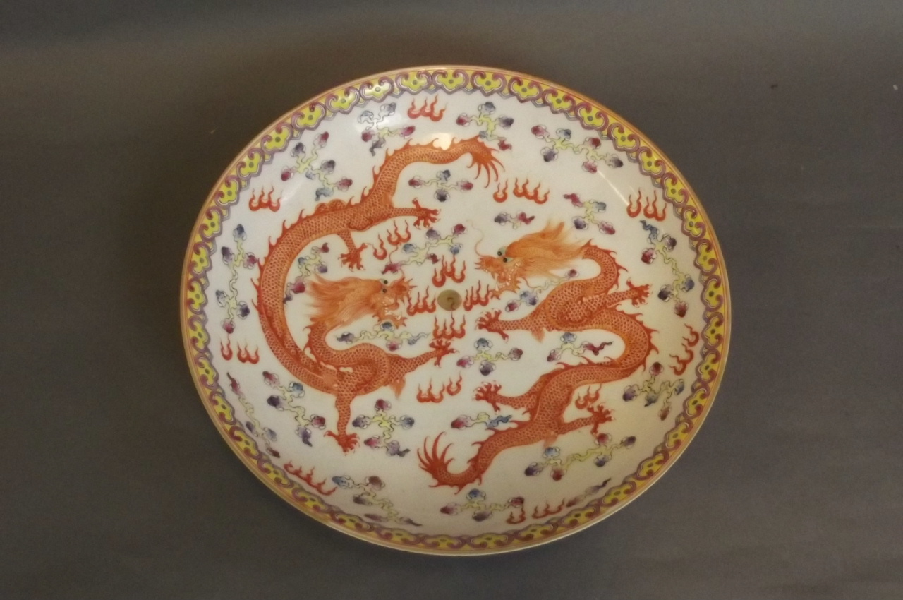 A Chinese white ground dish with painted polychrome enamel decoration of 2 dragons chasing the