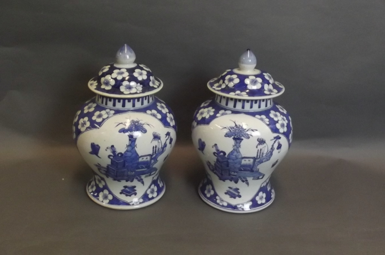 A pair of blue and white Chinese jars and covers with painted cracked ice and prunus blossom