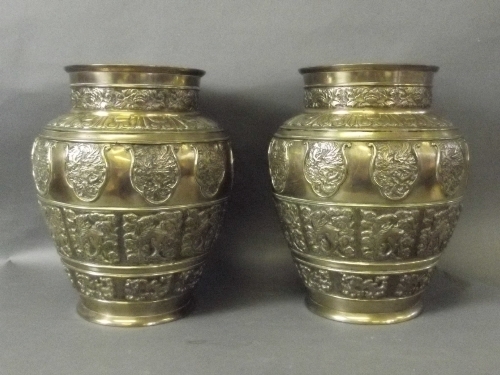 A pair of Eastern bronze vases with raised panels of mythical beast decoration to sides, 10'' high
