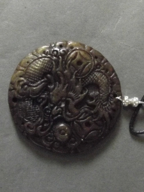 A Chinese jadeite pendant carved with a dragon and symbols, 2'' diameter