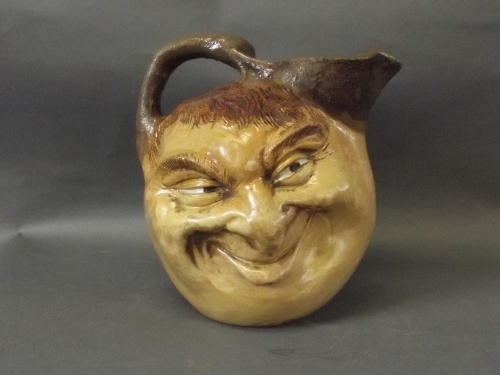 An art pottery stoneware 'ugly' jug with 2 faces to side, 8'' high