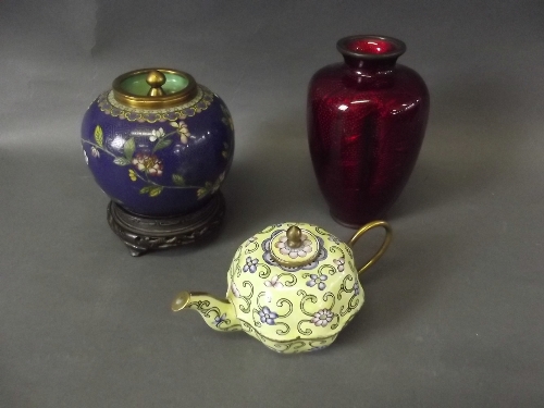 A cloisonné pot and cover on a carved wood base, an enamelled Chinese brass teapot with floral
