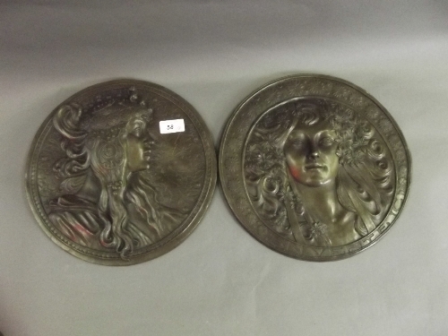 A pair of Art Nouveau style circular bronze wall plaques depicting maidens, 11¾'' diameter