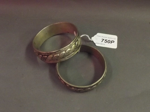 A pair of Eastern low grade silver ornate bangles