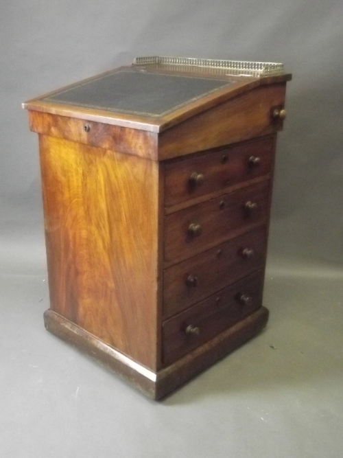 A Victorian mahogany Davenport with sliding leathered top and brass gallery, standing on a plinth