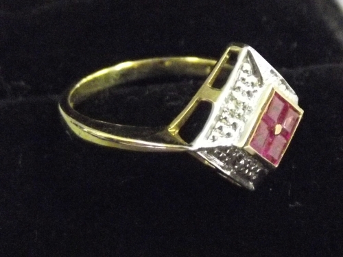 A 9ct gold lady's ring with four rubies set on a diamond cluster cushion and pierced shoulder,