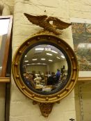 Regency style convex mirror in gilt ball frame with eagle pediment.