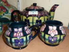 Walter Moorcroft Sally Tuffin Violet pattern three piece tea set comprising teapot, sugar bowl and
