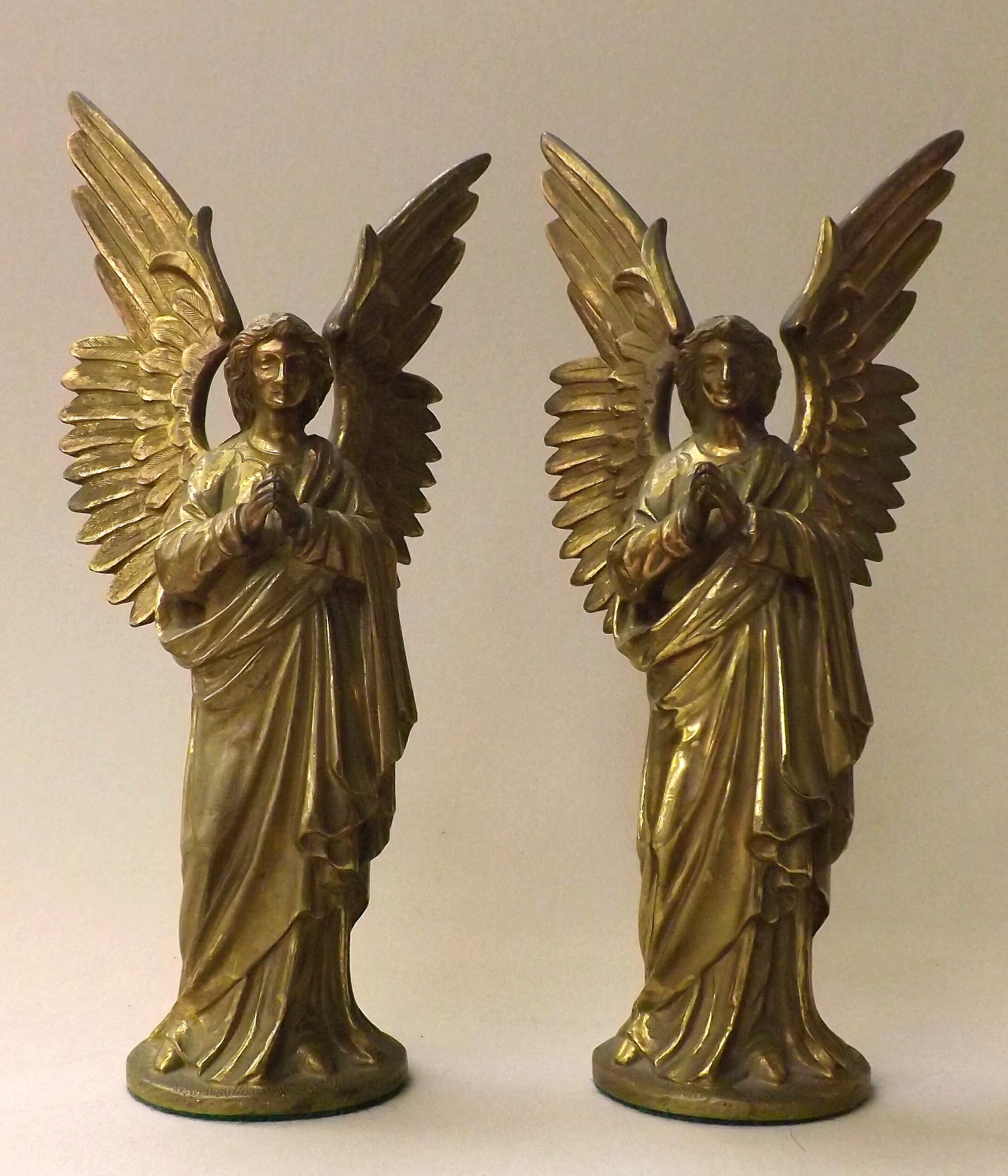 A pair of brass angel figures cast with their wings outstretched, classically draped and with