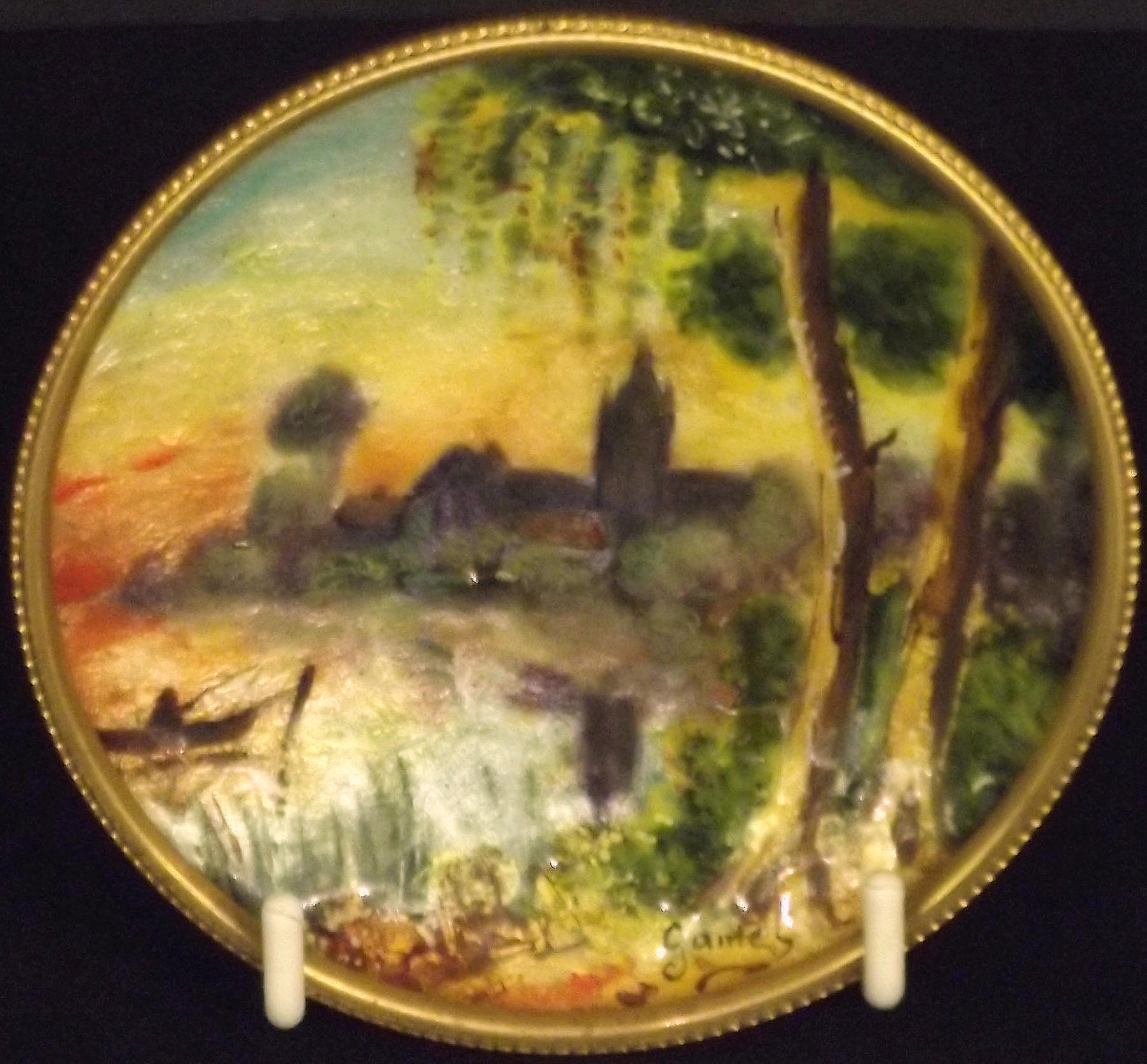 A late 19th century French circular enamel pin dish, decorated a river scene, signed Gamet, diameter