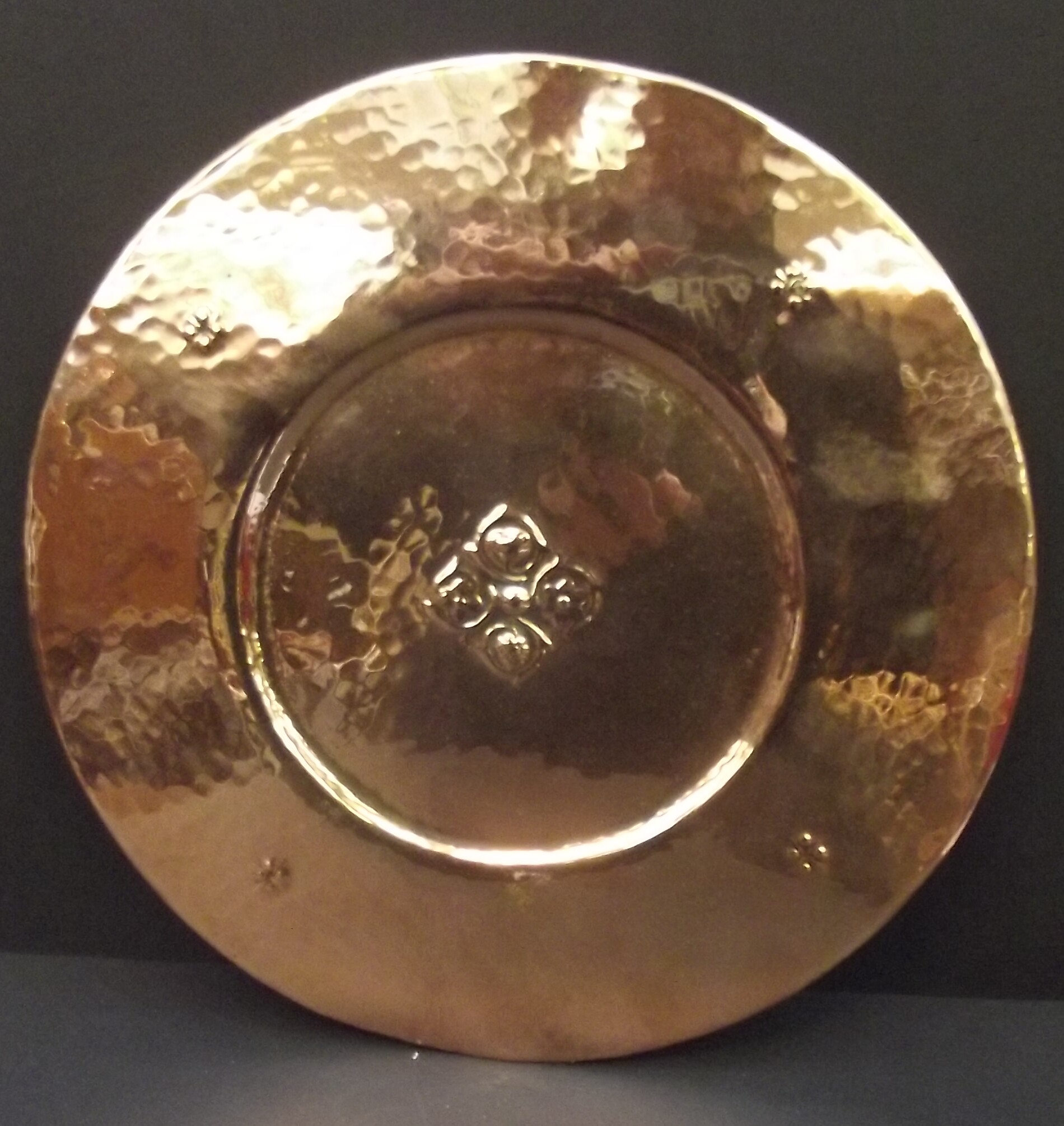 An Arts and Crafts copper circular wall plaque to the centre embossed a flower head, diameter 24.