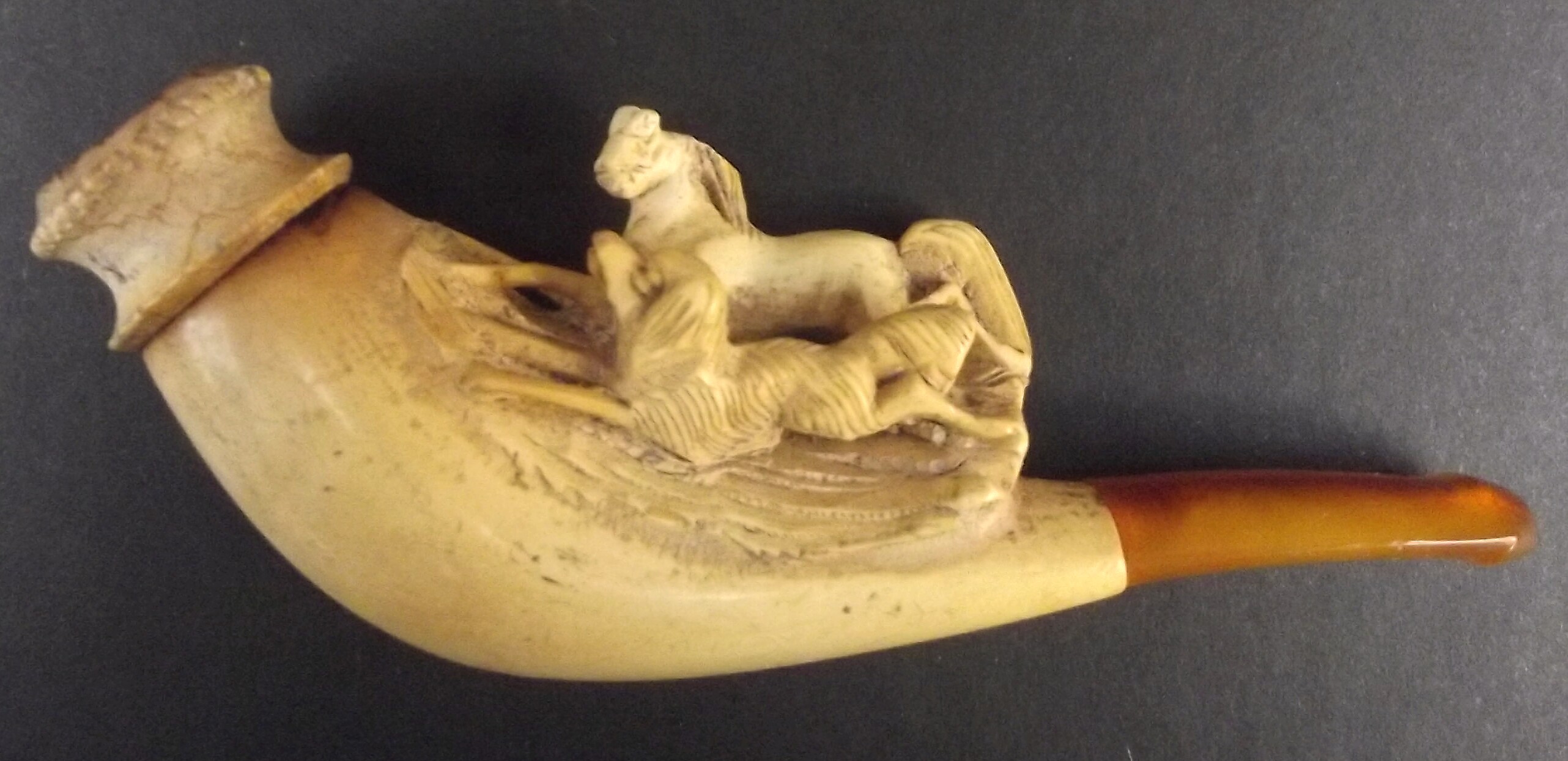 A cased meerschaum sheroot holder with amber mouth piece carved with a horse and hound.