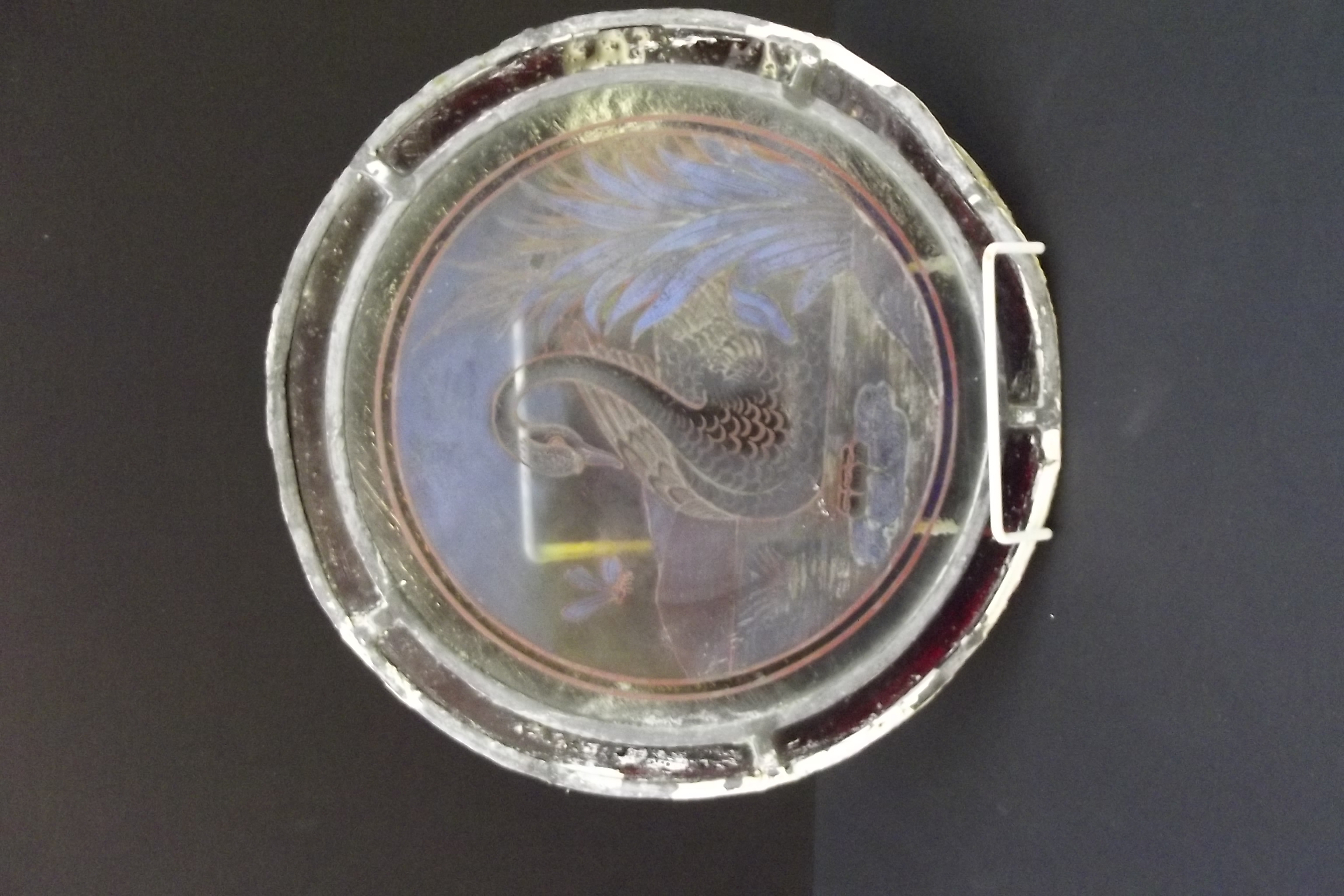 A circular leaded stained glass window panel painted with a swan in water, diameter 27cm.